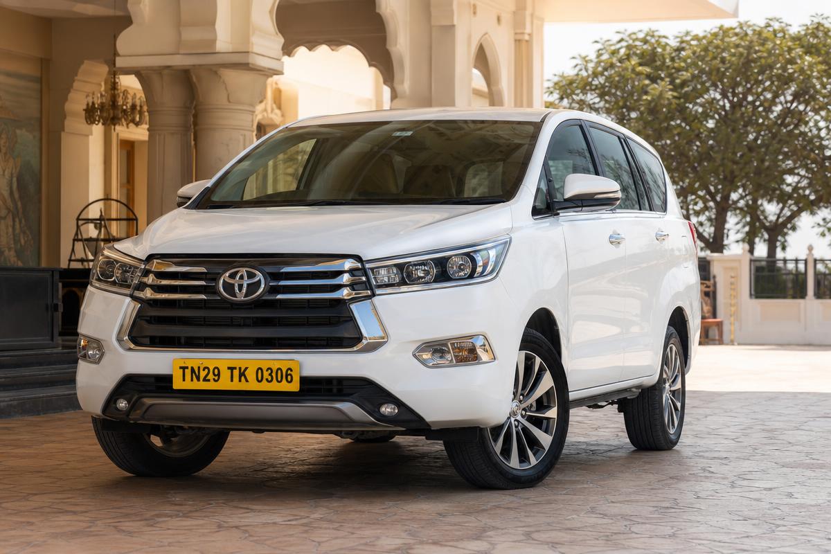 Toyota Innova Crysta · TN29 TK 0306 Front three-quarter of a pearl white Toyota Innova Crysta chauffeur taxi, yellow Tamil Nadu commercial number plate TN29 TK 0306, at a Tamil Nadu heritage hotel portico in Dharmapuri — POLAAMAA™ Grand Tourer