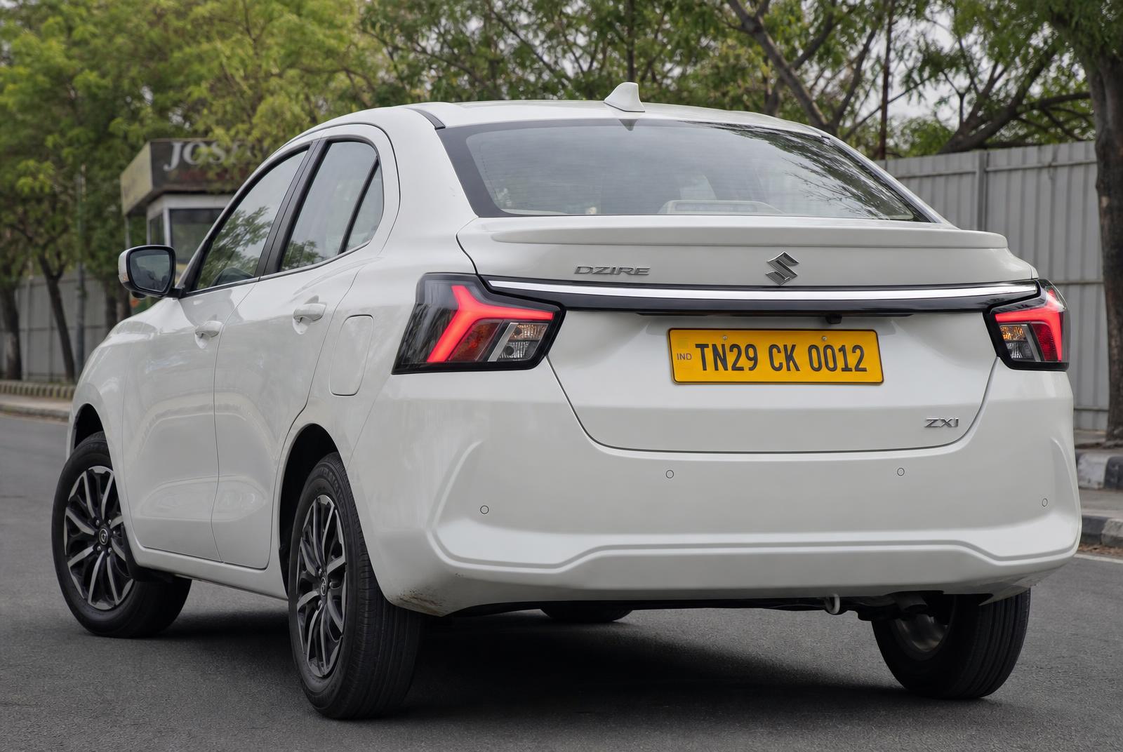 Maruti Suzuki Dzire · TN29 CK 0012 Rear three-quarter of a pearl white Maruti Suzuki Dzire chauffeur taxi, yellow Tamil Nadu commercial number plate TN29 CK 0012, at a Tamil Nadu heritage hotel portico in Dharmapuri — POLAAMAA™ Executive Sedan