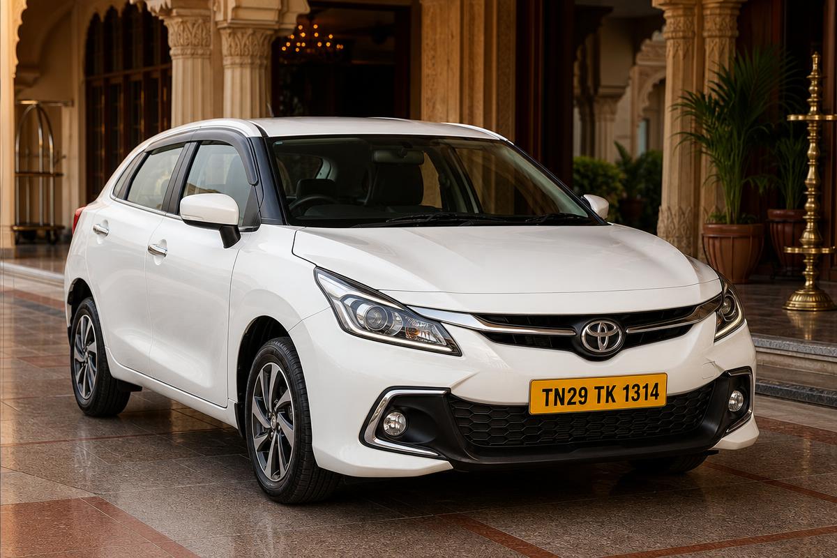 Toyota Glanza · TN29 TK 1314 Front three-quarter of a pearl white Toyota Glanza chauffeur taxi, yellow Tamil Nadu commercial number plate TN29 TK 1314, at a Tamil Nadu heritage hotel portico in Dharmapuri — POLAAMAA™ Premium Hatchback
